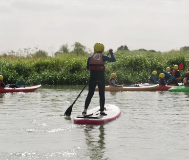 A youth standing on a board while in the river.